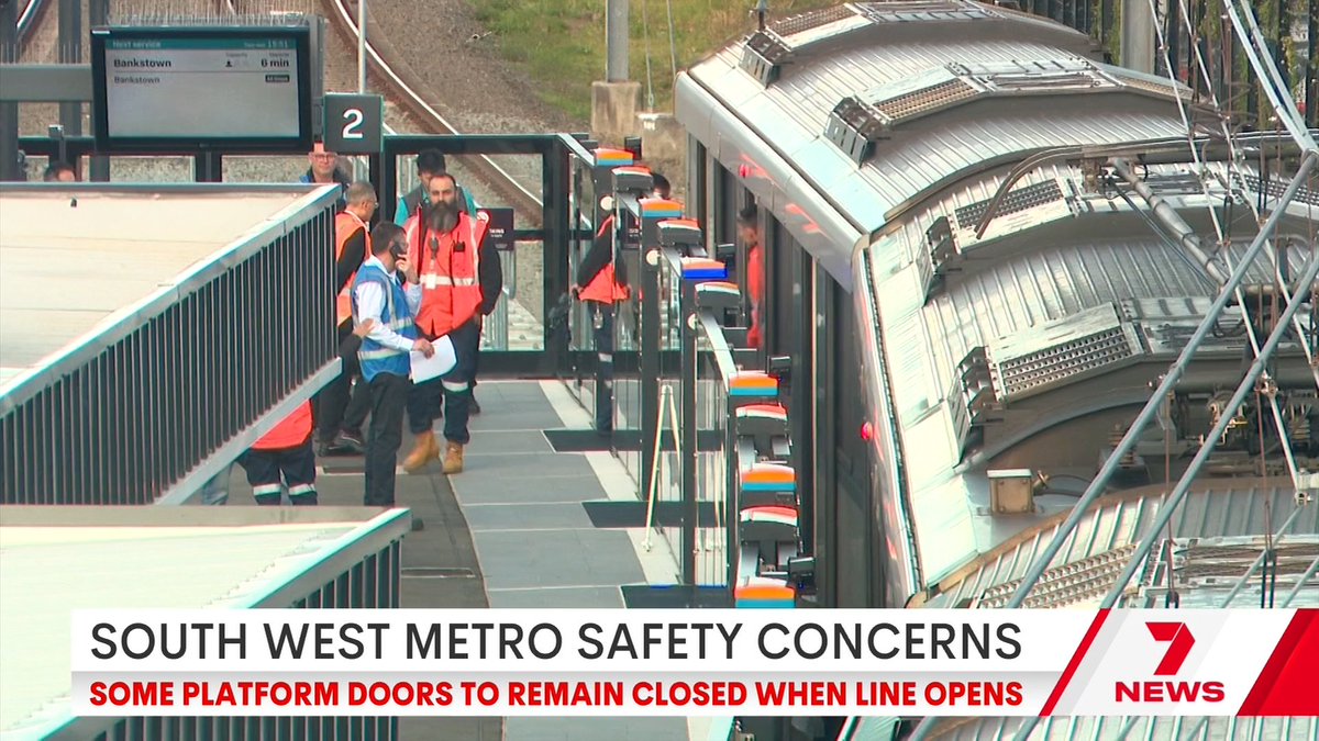 Workers inspect the train doors at a Bankstown-bound platform as a "South West Metro Safety Concerns" banner from Channel 7 News reports that some platform doors will remain closed when the line opens.