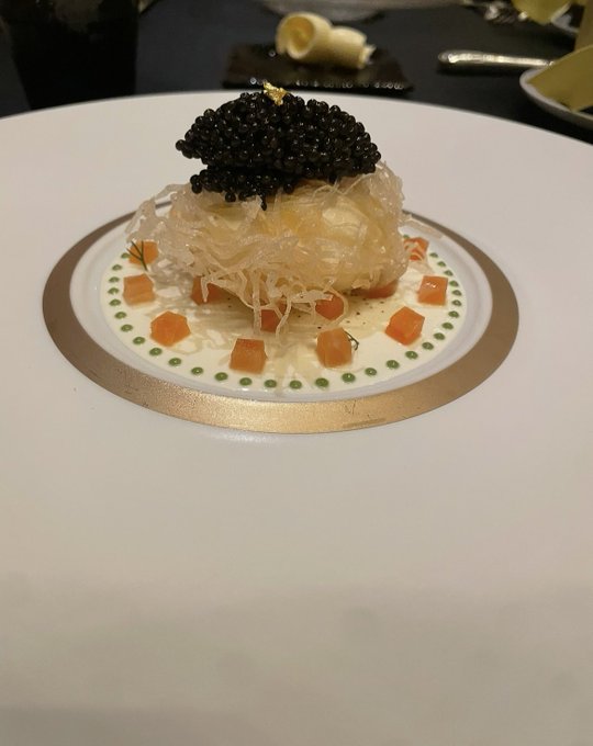 An elegant fine-dining dessert at Gastronomy Joël Robuchon featuring a delicate mound of shredded phyllo or angel hair pastry topped with a generous quenelle of black caviar, artfully plated with orange gelée cubes and a ring of green dots on a gold-rimmed plate—befitting the luxurious birthday celebration described in the caption.