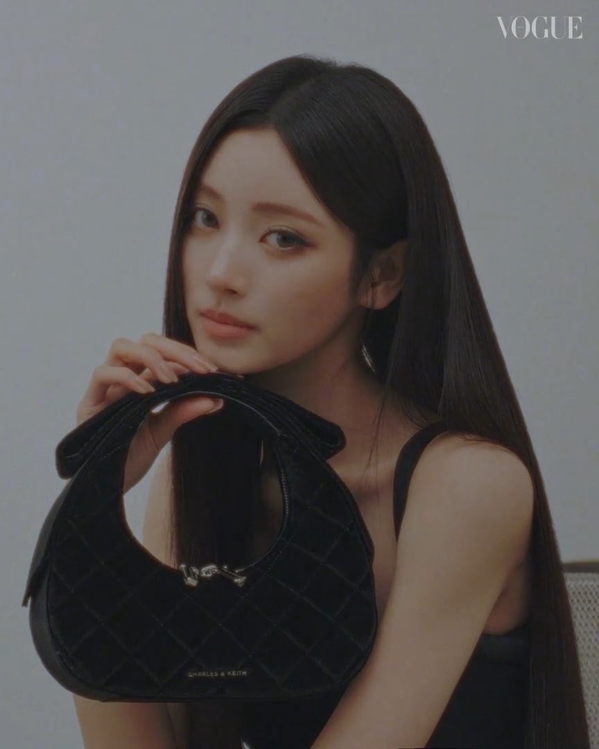 A Vogue editorial photo of a young woman with long dark hair holding a black quilted Charles & Keith handbag against a plain background, with the VOGUE logo in the top right corner.