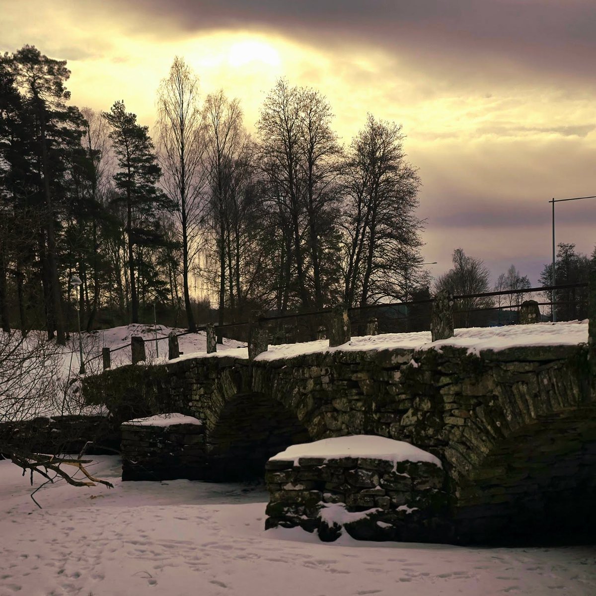 allancesa01's tweet photo. Gammal, övergiven stenbro i vinterlandskapet utanför Borås. Snön ligger tyst över marken och fotspåren leder mot den stilla, frusna ån. Himlen brinner i mjuka toner av guld och grått - en plats där tiden verkar ha stannat. #Borås #SvenskVinter https://t.co/16xRnI0nom
