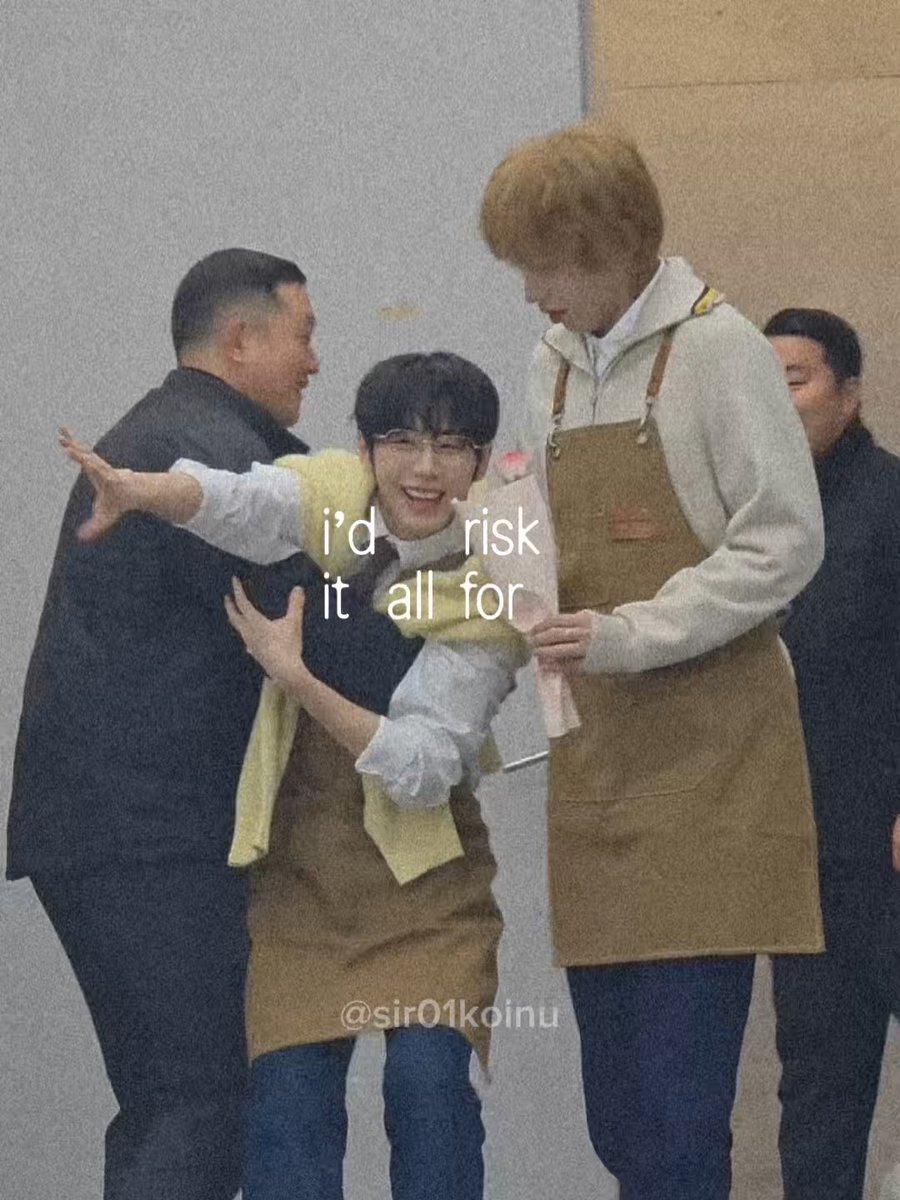 Three men in aprons are captured in a candid moment; the central figure with glasses has his arm extended while the blonde man on the right holds a bouquet, with text overlay reading 'i'd risk it all for' and a watermark '@sir01koinu'.
