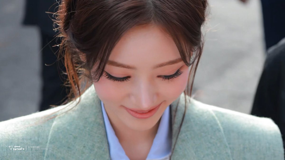 Anna of MEOVV looks down with a soft smile, her elegant updo and refined makeup highlighting her poised appearance at the Chloé 261001 event.