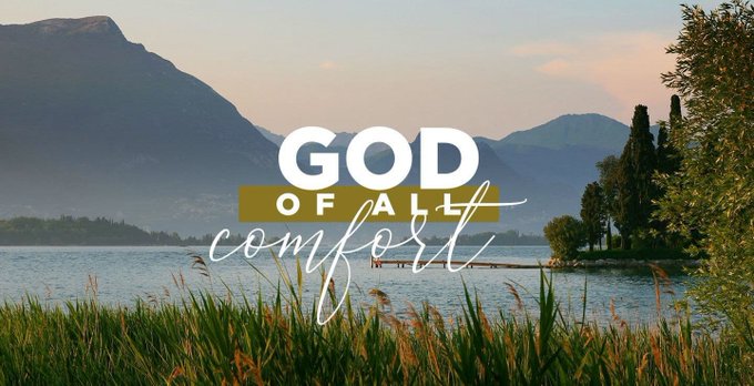 A scenic photo of a lake with mountains in the background, overlaid with the text "GOD of all comfort" in stylized white and gold lettering.