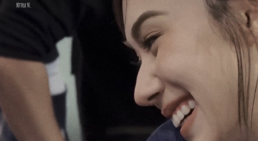 A close-up profile shot captures a smiling woman with prominent eyeliner and a bright, joyful expression, with the watermark "NITRA N." visible in the upper left corner. The image aligns with the caption's message encouraging "Lalina Lena" to smile more often, celebrating her radiant smile in this PLPL Issey Miyake campaign moment.