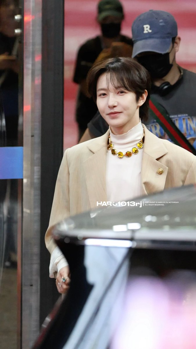 A young person with short dark hair wears a beige blazer over a white turtleneck, accessorized with a bold gold statement necklace featuring large round stones, posing with a slight smile as a watermark "HARU1013rh COPYRIGHT © MARU1013 NOTDREAM ALL RIGHT RESERVED" appears across the image. The caption "and u will be eaten whole" pairs fittingly with the striking gold necklace, evoking the imagery of being consumed or devoured by its lavish, almost predatory allure.