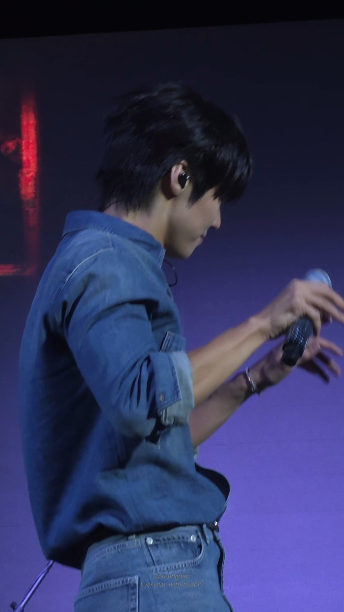A young man with an earpiece and blue denim shirt holds a microphone on a stage with purple lighting, watermark reads 'everyday with hyu00'.