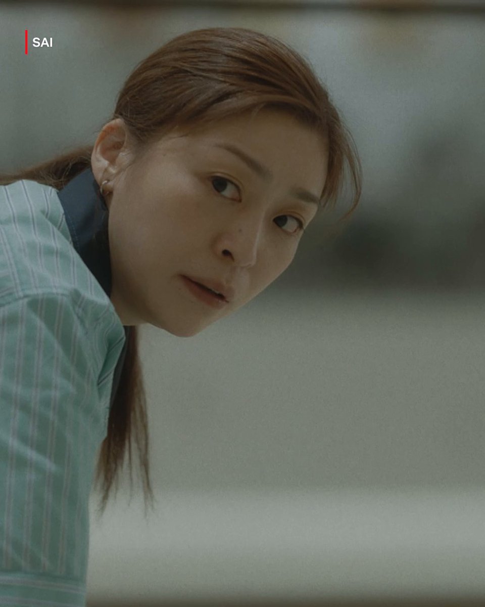A young woman with long brown hair, wearing a light blue striped shirt, peers intently forward with a focused, inquisitive expression. The "SAI" watermark appears in the top-left corner, framing a moment that visually echoes the post's theme of generational workplace dynamics—her intense gaze capturing the curiosity and determination often associated with a new generation entering the professional sphere.