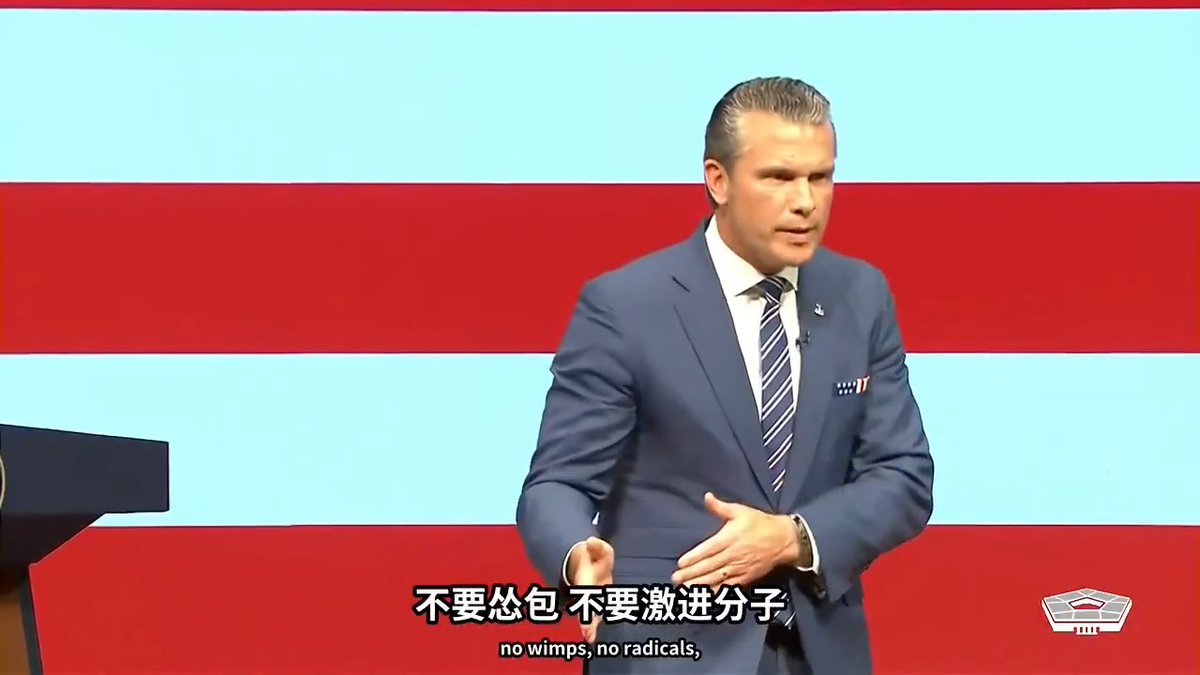 A man in a blue suit with a striped tie speaks at a podium against an American flag backdrop, with Chinese and English subtitles reading '不要怂包 不要激进分子' and 'no wimps, no radicals.'