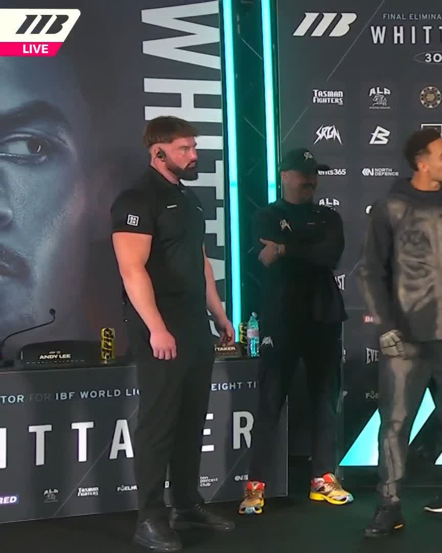 Tyson Ward scores as the face-off erupts into a tense verbal exchange alongside an official and a member of his team. The scene takes place at the final elimination press conference backdrop, which prominently displays "IBF," "WHITTAKER," and "#WhittakerWallace" branding, reflecting the heated pre-fight face-off described in the post.