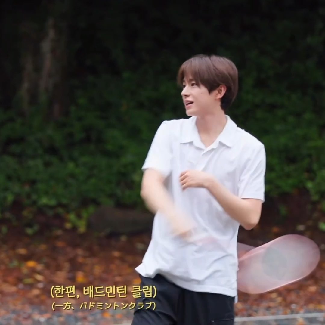 A young man in a white polo shirt plays badminton outdoors, accompanied by Korean text reading "(한편, 배드민턴 클럽)" meaning "Meanwhile, Badminton Club"—the "meanwhile" caption humorously framing this club scene as a parallel subplot to the main K-drama cliché described in the post, where every girl waits at the gym just to glimpse the cool badminton club senior Yuushi.