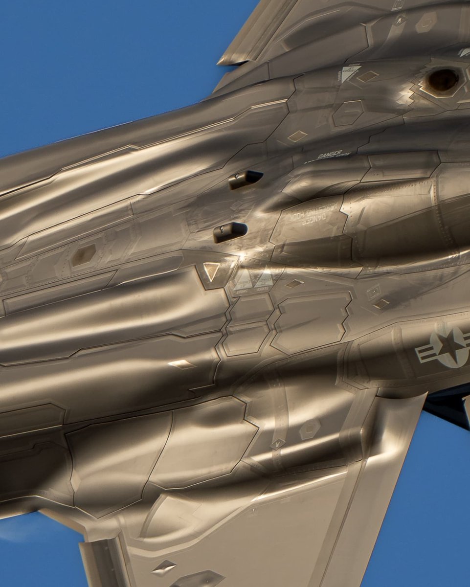 Arkasiraee's tweet photo. The F-35 was designed around a difficult constraint, almost no part of its external geometry can serve only one purpose.

Those long curves and aligned edges have to control where radar energy is scattered while still producing a fighter that flies well. 

Behind that surface, engineers had to fit fuel, landing gear, internal weapons, sensors, cooling systems and an enormous F135 engine. 

Even the separate Integrated Power Package needs somewhere to exhaust. Stealth doesn't remove any of these compromises. It means their electromagnetic consequences have to be hidden.

This is why the F-35 isn't simply an aerodynamic aircraft covered in radar absorbing material. Its shape is part of the stealth system. Electromagnetic modelling predicts how radar energy interacts with that geometry, while cavities, exposed machinery and badly positioned edges can create strong returns. 

Weapons disappear inside the aircraft, doors close back into the outer shape, and even an access panel becomes part of the problem.

Then you actually have to manufacture it.

A compound-curved composite skin has to emerge at almost exactly the intended contour and meet the next panel without the joint undoing what the shaping achieved. 

Multiply that across thousands of fasteners, removable panels, landing-gear doors, weapon bays and nearly half a mile of seams, and something as ordinary as a panel gap becomes part of the aircraft's stealth engineering.

And it has to remain that precise after years of flying. Fillers and low-observable coatings help control electromagnetic behaviour around those joints, but aircraft live outside. Rain, dust, salt, fluids and maintenance gradually wear those coatings. Opening a panel can mean restoring the low-observable surface around it before the aircraft flies again.

What appears to be one smooth, flowing shell is actually thousands of manufactured pieces, openings and interfaces being made to behave, as closely as possible, like one deliberately designed stealth surface.
