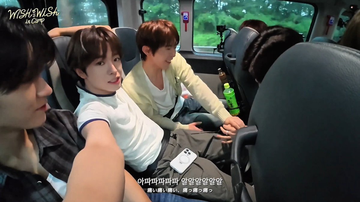 A screenshot from a vlog titled 'WiSH in Camp' showing several young men sitting inside a van, with Korean and Japanese subtitles at the bottom.
