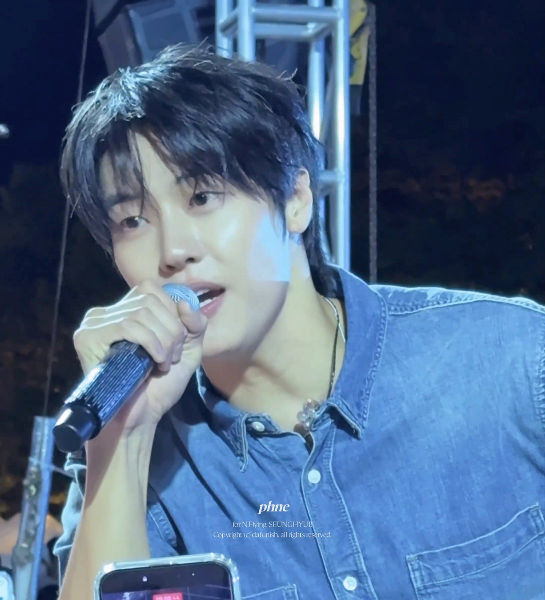 A performer with dark hair holding a microphone and singing, wearing a denim shirt, with a watermark reading 'phne for N.Flying SEUNGHYUB Copyright (c) dafunish. all rights reserved.'