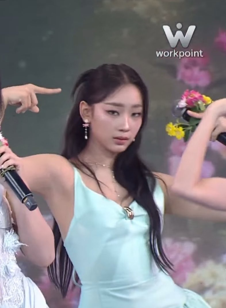 Screenshot from Workpoint channel showing a young woman with long dark hair in a mint green top holding a bouquet of flowers on stage.