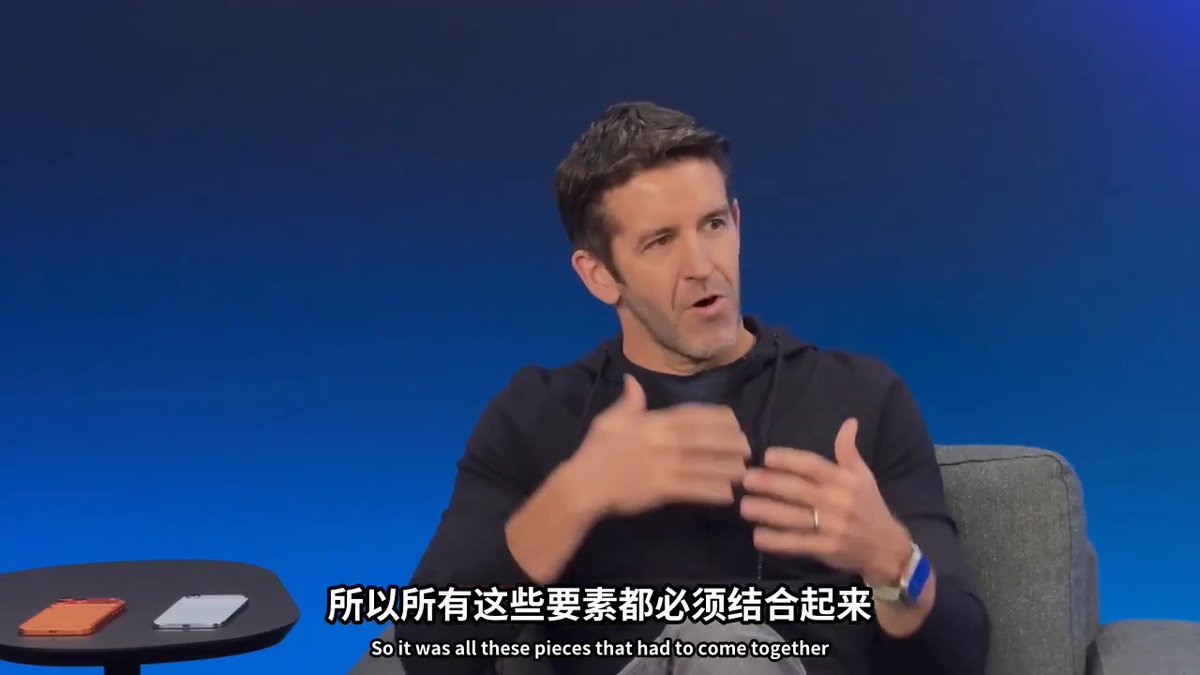 Apple's CEO John Ternus speaks during an interview against a blue backdrop, gesturing with both hands as he explains the development of the iPhone Air. Subtitles read "So it was all these pieces that had to come together" in both Chinese and English, with two iPhones visible on a table beside him.