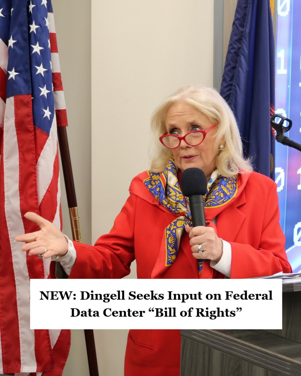 A blonde woman wearing red glasses, a bright red jacket, and a patterned scarf speaks into a handheld microphone while gesturing beside an American flag. A headline banner is overlaid across the bottom of the image.