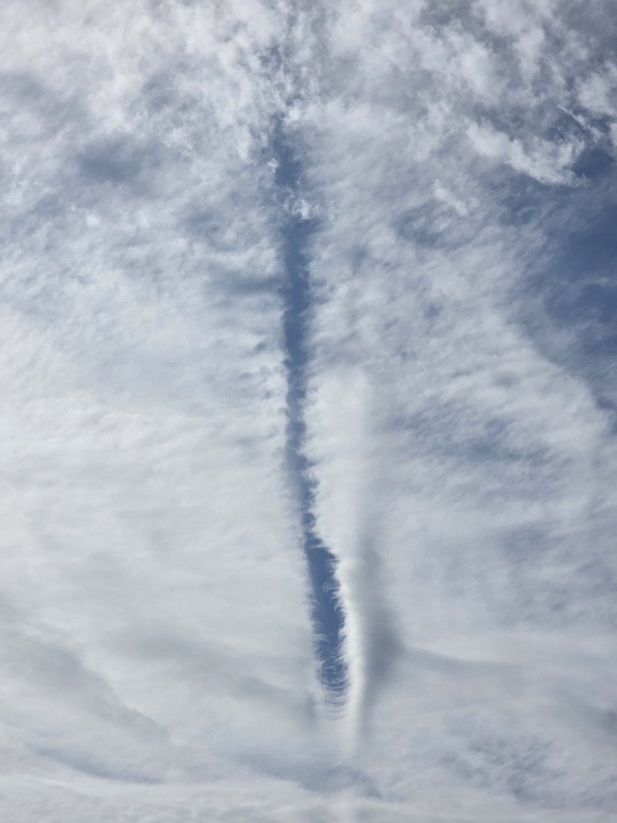 SaMMastOff's tweet photo. A Zipper in the Sky: Rare Physics or Something More?

At first glance, what we see here is a known atmospheric phenomenon—a dissipation trail (or distrail). In classical meteorology, it occurs when an aircraft flies through a thin layer of clouds, where its engine heat and wing turbulence evaporate supercooled water droplets, carving a clear blue channel through the cloud deck.

However, a closer look reveals several puzzling anomalies. The scale of the gap seems entirely out of proportion for a conventional airliner: it is far too wide and voluminous for a relatively small aircraft body. Furthermore, this "cut" lacks typical entry and exit paths—the trail begins and ends abruptly right in the middle of the sky canvas, without a long lead-in or exit tail.

Stepping outside standard explanations to consider an interaction with an unidentified object, these details form an intriguing picture:

1. Local Impulse or Gravitational Rupture: The rift resembles the trajectory vector of an object moving at extreme velocity, where localized shifts in pressure or temperature instantly dispersed the clouds along its path. The absence of a long entry/exit trail suggests a point-source or instantaneous interaction—as if an object materialized at that precise location, exerted a force on the atmosphere, and altered its trajectory or state.

2. Large-Scale Field Footprint: Because the gap vastly exceeds the dimensions of a standard aircraft, it resembles the footprint of a force or energy field surrounding a large object operating under optical concealment (stealth). While the craft itself remains invisible, its energy boundary leaves a physical signature in the cloud structure.

3. Spatial Energy Piercing: The limited extent and the refined geometry of the condensed cloud wisps at the lower tip resemble the mark of a targeted beam or a brief opening of a channel between atmospheric layers.

Official models explain images like this through natural evaporation processes. Yet the grand scale and distinct localization of this "zipper" in the sky leave room for a compelling question: what exactly possessed enough localized energy to leave such a mark?