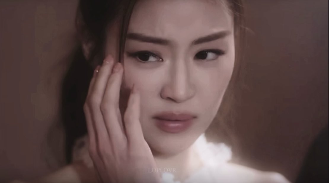 A close-up shot shows a young woman with long dark hair touching her face with her hand in what appears to be a dramatic scene with a watermark 'LOPLOVR'.