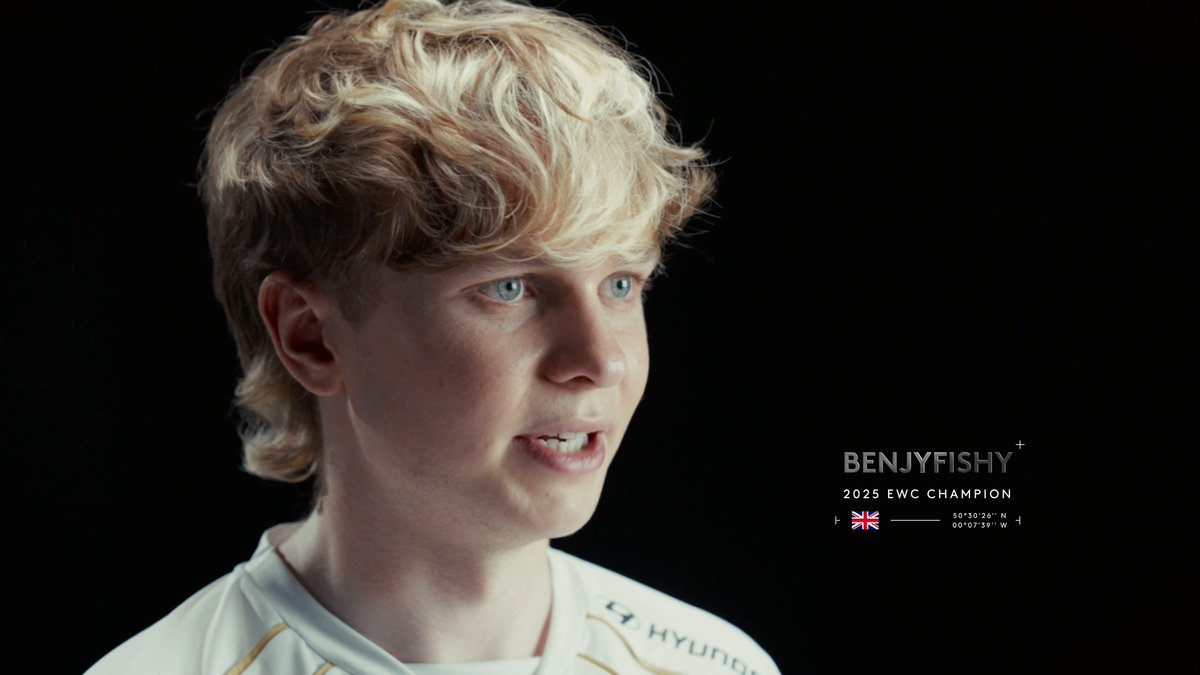 A young blond-haired gamer looks off to the side in profile against a black background, with text overlay reading "BENJYFISHY + 2025 EWC CHAMPION" alongside a British flag, dates (00°00'39"N, 00°07'39"W), and a partial "HYUNDAI" sponsor logo on his white jersey. The image ties to the post as a promotional portrait of pro player benjyfishy, who tested the new PRO X3 SUPERSTRIKE gaming peripheral.