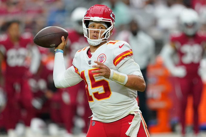 Patrick Mahomes, wearing his #15 Kansas City Chiefs white away jersey, prepares to throw a pass while looking downfield during a game. The image complements the post by illustrating the quarterback whose low average depth of target tops the list of NFL passers with at least 75 dropbacks this season.