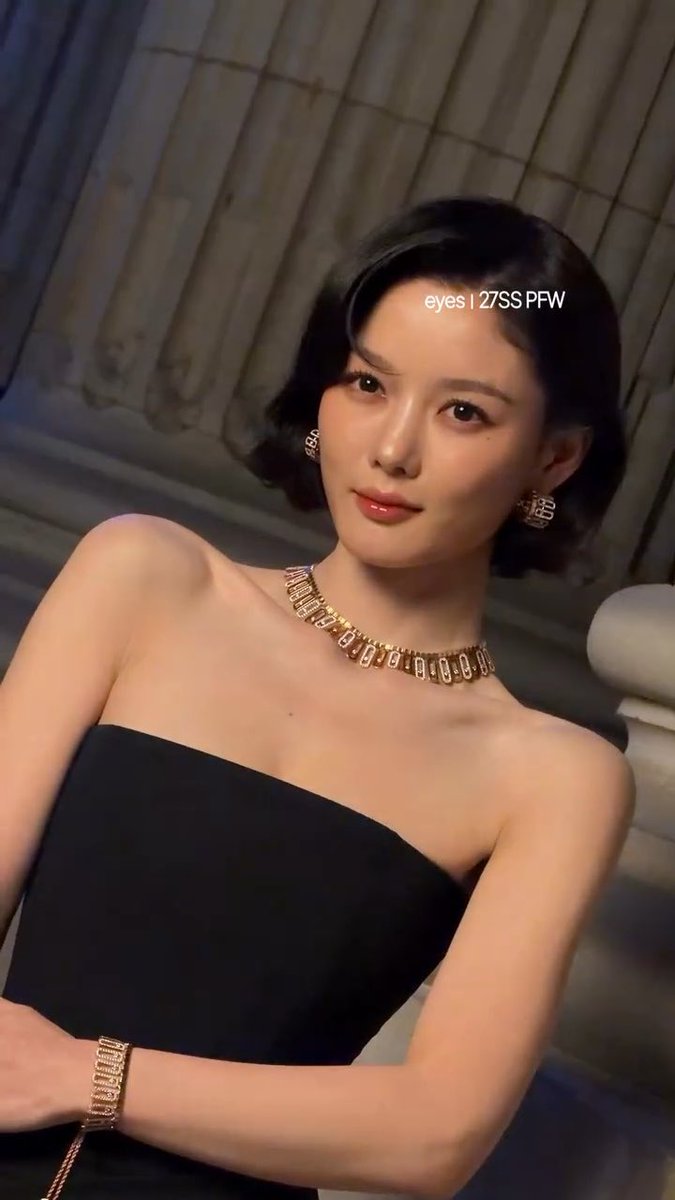 A young woman with short black hair wearing a black strapless top and a gold choker necklace, with text overlay reading 'eyes | 27SS PFW'.