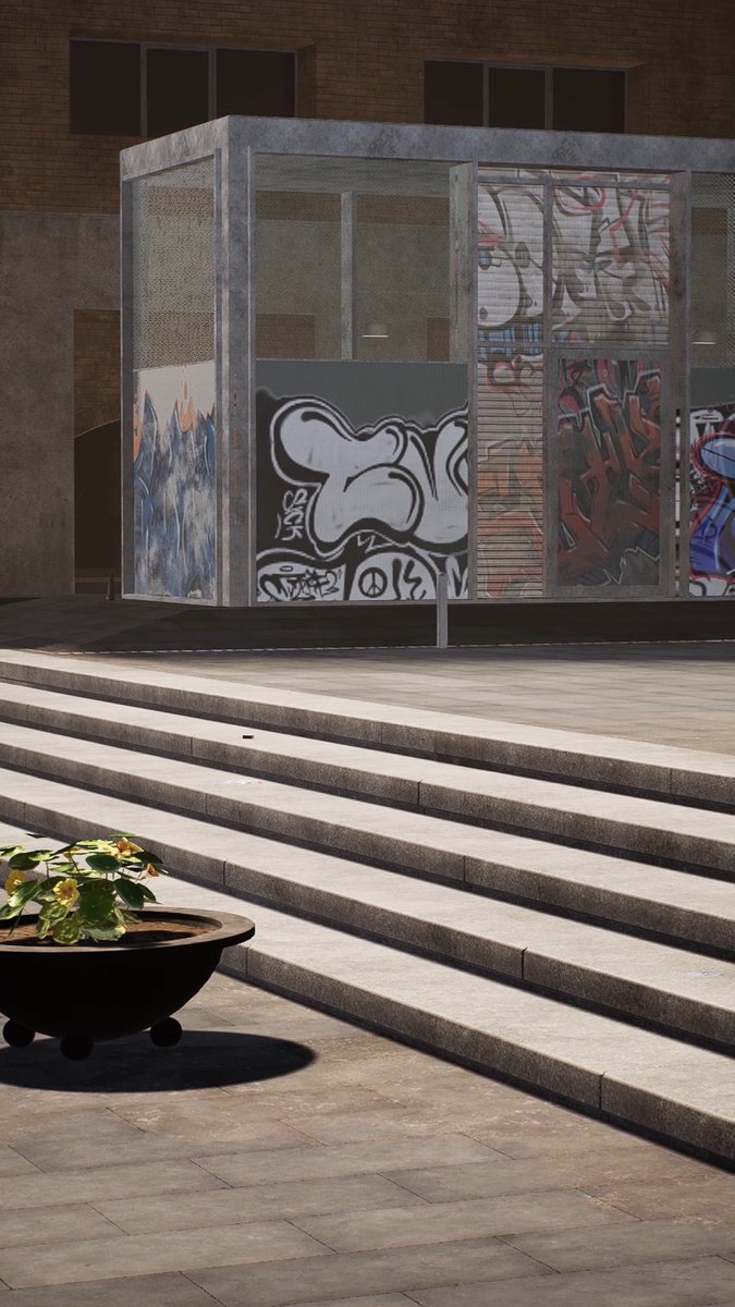 An urban scene featuring a structure covered in colorful graffiti, viewed from behind wide stone steps with a potted plant in the foreground.