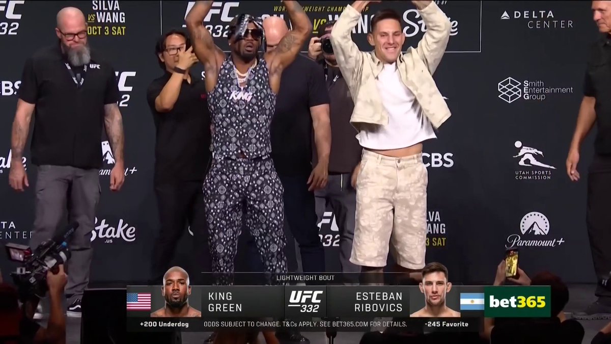 Two UFC fighters, King Green and Esteban Ribovics, face off at a UFC 332 weigh-in, with both raising their arms on stage against a backdrop featuring sponsor logos like Stake, CBS, and Paramount+. The on-screen graphics confirm the lightweight bout, listing Green as a +200 underdog and Ribovics as a -245 favorite.