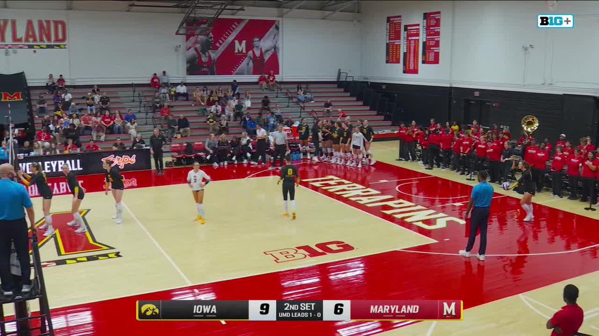 A volleyball game between Iowa and Maryland with the scoreboard showing Iowa 9, Maryland 6 in the 2nd set, played on a red court marked 'TERRAPINS' with the B1G logo.