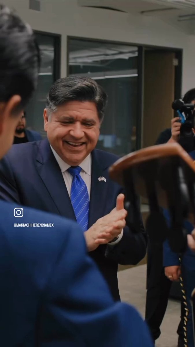 A man in a blue suit and blue striped tie, wearing a small American flag pin, smiles broadly while shaking hands in what appears to be an office setting; an Instagram watermark reads "@MARIACHIHERENCIAMEX".