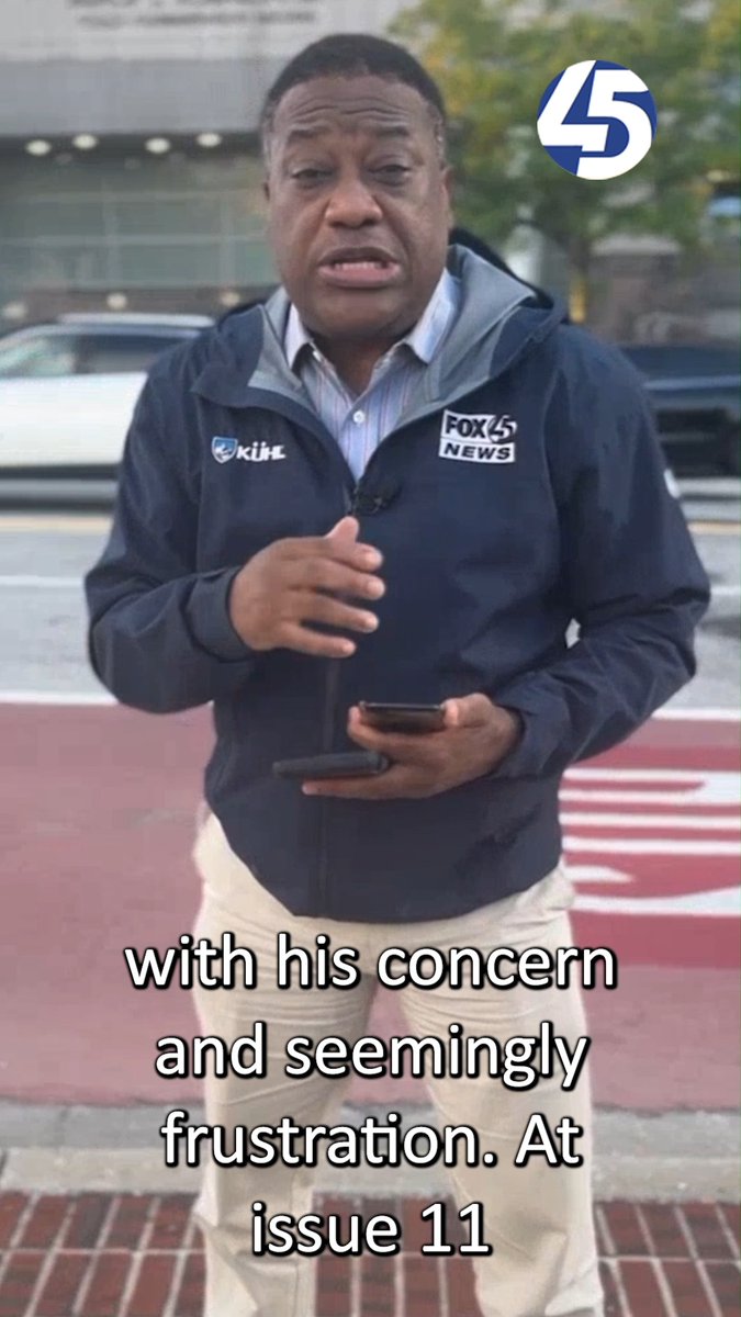 A news reporter wearing a 'FOX 45 NEWS' jacket and 'KISS' microphone stands outdoors holding a phone, with subtitle text reading 'with his concern and seemingly frustration. At issue 11' and a '45' logo in the corner.