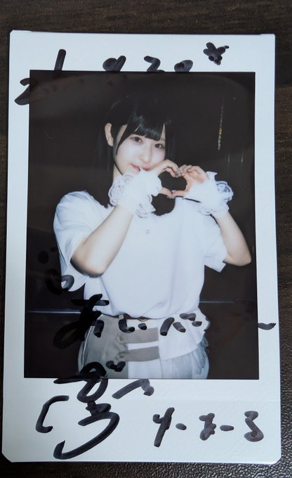 An autographed polaroid photo of a Japanese idol or performer making a heart shape with her hands, dated 4.8.3, with handwritten Japanese characters across the bottom.
