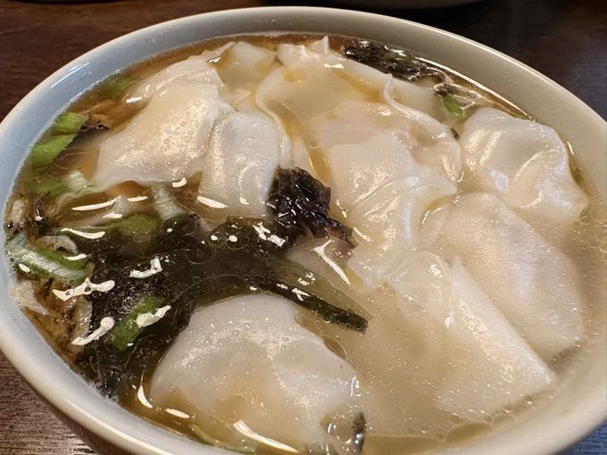 A bowl of homemade chicken soup dumplings, brimming with a clear broth and generously topped with seaweed, dried shrimp, and preserved vegetables as described in the post.