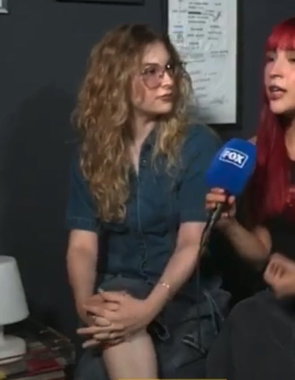 Two women are being interviewed, with a microphone labeled 'FOX' visible. One woman has curly hair and wears sunglasses, while the other has red hair and bangs.