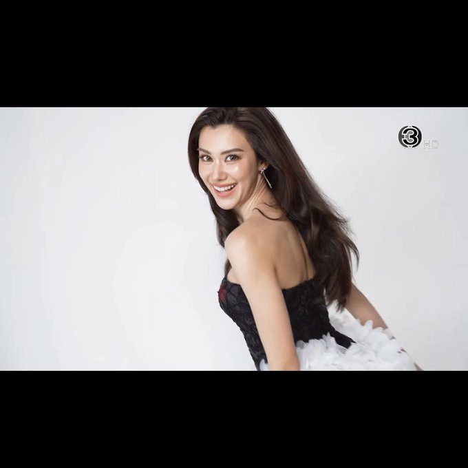 A woman with long dark hair smiles over her shoulder while wearing a black and white strapless dress against a white background, with a Channel 3 HD logo visible.