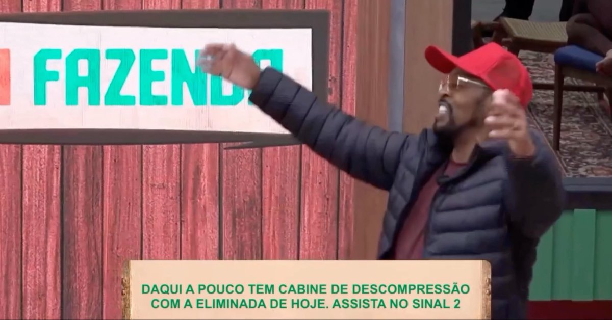 A man in a red cap and dark jacket gestures with both arms raised in front of a sign reading "FAZENDA", with a Portuguese text overlay about a decompression booth.