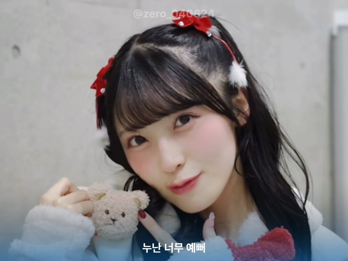 A young woman with dark hair wears festive red bow hair accessories with white pom-poms, holding a small brown teddy bear, with Korean text '누난 너무 예뻐' and watermark '@zero_040624' visible.