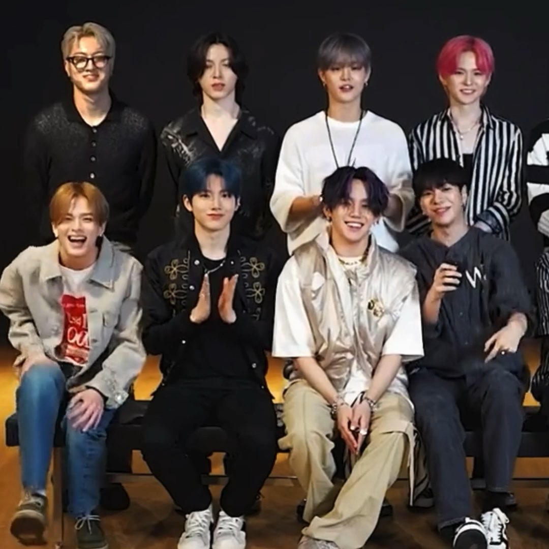 A group photo of eight K-pop idols posing together against a dark background.