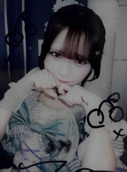 A selfie of a young woman with dark hair and bangs, wearing a patterned dress, posing with her hands near her face; the photo has graffiti-style doodles drawn over it.