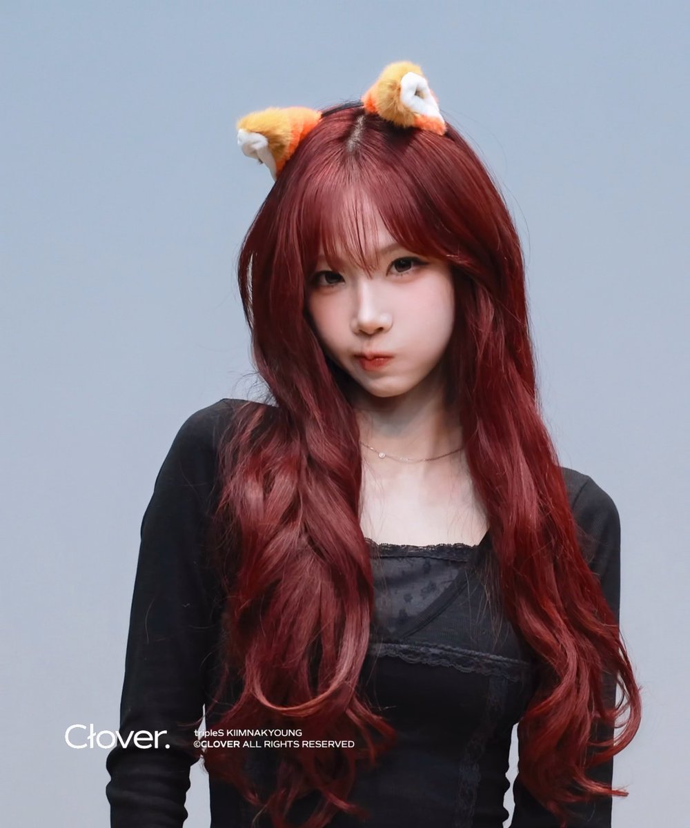 A portrait of a young woman with long red hair wearing orange animal ears and a black top, with 'Clover.' and 'tripleS KIMNAKYOUNG ©CLOVER ALL RIGHTS RESERVED' watermarked at the bottom.