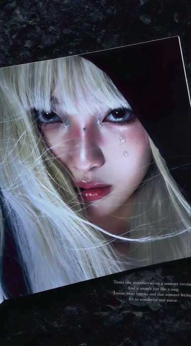 An artistic close-up portrait of a woman with blonde hair, pale eyes, and decorative face gems, with a small poem about strawberries visible in the corner.
