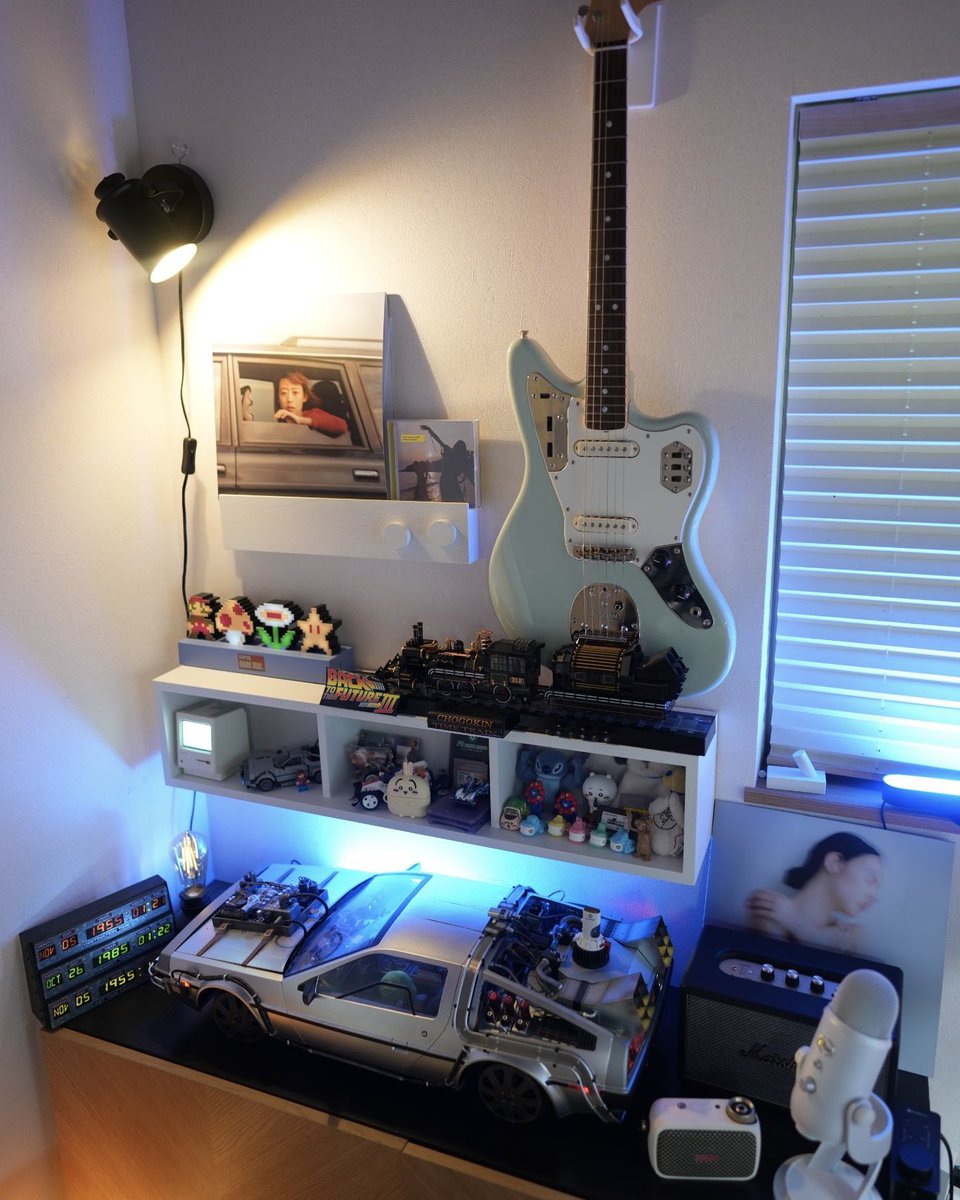 preducts_inc's tweet photo. USER SETUP | PREDUCTS DESK - POLAR

ホワイトとライトグレーでライトトーンな印象のデスク「PREDUCTS DESK - POLAR」。今回はPOLARを愛用いただいている、YouTubeチャンネル「THE オトウサンノヒミツキチ」を運営する @dadsecretbase さんのデスクをご紹介します。

動画制作にとどまらず、ものづくりや他社との仕事まで、日々の制作活動をこの環境で進めているKeiさん。6畳の和室にYouTubeスタジオを兼ねたワークスペースを構え、「秘密基地感」をテーマに、デジタルとアナログが混在したワクワクする仕事環境をつくることを大切にされています。

デスクは作業用と撮影用の2台をL字に配置。作業のしやすさに加え、限られた空間でも動画の絵づくりができるようにという意図があるそうです。

作業用のデスクにはデスクマットを敷き、キーボードやマウスといった入力デバイスに加え、ノートやペン、メガネなど使用頻度の高い小物を手の届く位置に配置しています。

収納は天板裏とDASHBOARDに集約。天板裏にはTray for DESKを、DASHBOARDにはSystem Tray forとRig Gadget Armを取り付け、カメラやStream Deck、SSDなどもDASHBOARD上に常駐。点在しがちな機材を天板裏とDASHBOARDに振り分け、賑やかさはそのままに使い勝手を確保しています。

撮影用のデスクには、マイクやミキサーなど配信・収録に関わる機材に加え、DJコントローラーも並びます。

そして、この部屋で数年をかけて試行錯誤を重ねてきたのがライティング。撮影用の大型照明に加え、デスクにはBluetoothで色を変えられるテープライトを貼り、パソコンの背面や窓際にはPhilips HueのLEDを配置。背景には無印良品のライトやBenQの卓上ライトも組み合わせています。

LEDの色をガジェット感の強いトーンに振り切る。POLARのシンプルな色味が、そのLEDの色を素直に受け止めてくれるといいます。

ガジェット類が並ぶ有孔ボード、壁に掛けたギター、「バック・トゥ・ザ・フューチャー」のデロリアンモデル。実用と"好き"が入り混じっているのが、この空間の持ち味です。
