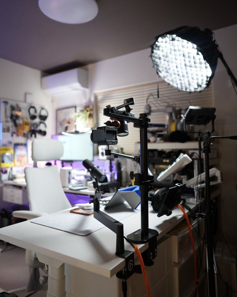 preducts_inc's tweet photo. USER SETUP | PREDUCTS DESK - POLAR

ホワイトとライトグレーでライトトーンな印象のデスク「PREDUCTS DESK - POLAR」。今回はPOLARを愛用いただいている、YouTubeチャンネル「THE オトウサンノヒミツキチ」を運営する @dadsecretbase さんのデスクをご紹介します。

動画制作にとどまらず、ものづくりや他社との仕事まで、日々の制作活動をこの環境で進めているKeiさん。6畳の和室にYouTubeスタジオを兼ねたワークスペースを構え、「秘密基地感」をテーマに、デジタルとアナログが混在したワクワクする仕事環境をつくることを大切にされています。

デスクは作業用と撮影用の2台をL字に配置。作業のしやすさに加え、限られた空間でも動画の絵づくりができるようにという意図があるそうです。

作業用のデスクにはデスクマットを敷き、キーボードやマウスといった入力デバイスに加え、ノートやペン、メガネなど使用頻度の高い小物を手の届く位置に配置しています。

収納は天板裏とDASHBOARDに集約。天板裏にはTray for DESKを、DASHBOARDにはSystem Tray forとRig Gadget Armを取り付け、カメラやStream Deck、SSDなどもDASHBOARD上に常駐。点在しがちな機材を天板裏とDASHBOARDに振り分け、賑やかさはそのままに使い勝手を確保しています。

撮影用のデスクには、マイクやミキサーなど配信・収録に関わる機材に加え、DJコントローラーも並びます。

そして、この部屋で数年をかけて試行錯誤を重ねてきたのがライティング。撮影用の大型照明に加え、デスクにはBluetoothで色を変えられるテープライトを貼り、パソコンの背面や窓際にはPhilips HueのLEDを配置。背景には無印良品のライトやBenQの卓上ライトも組み合わせています。

LEDの色をガジェット感の強いトーンに振り切る。POLARのシンプルな色味が、そのLEDの色を素直に受け止めてくれるといいます。

ガジェット類が並ぶ有孔ボード、壁に掛けたギター、「バック・トゥ・ザ・フューチャー」のデロリアンモデル。実用と"好き"が入り混じっているのが、この空間の持ち味です。