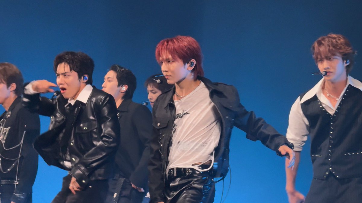 A K-pop group performs energetically on stage against a vibrant blue backdrop, with members sporting edgy leather jackets, stylish outfits, and in-ear monitors while executing dynamic choreography. The hashtag "#펜타곤" (Pentagon) and "GORILLA" reference the group's iconic track, captured here mid-performance likely during their 2026 tour rehearsals or show.