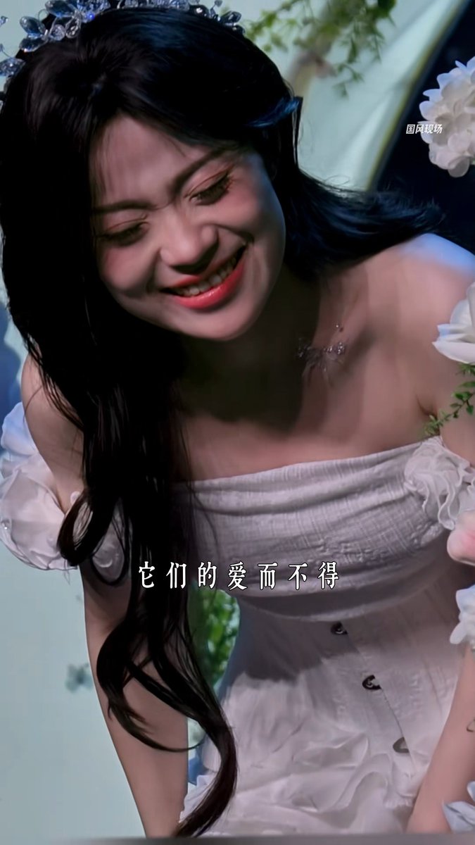 A young woman wearing a white dress and floral headpiece smiles warmly while looking downward, surrounded by white flowers. The Chinese subtitle reads "它们的爱而不得" (Their love unattainable), and the scene's emotional resonance aligns with the post's description of a song so moving it brought the singer to tears, touching the soul deeply.
