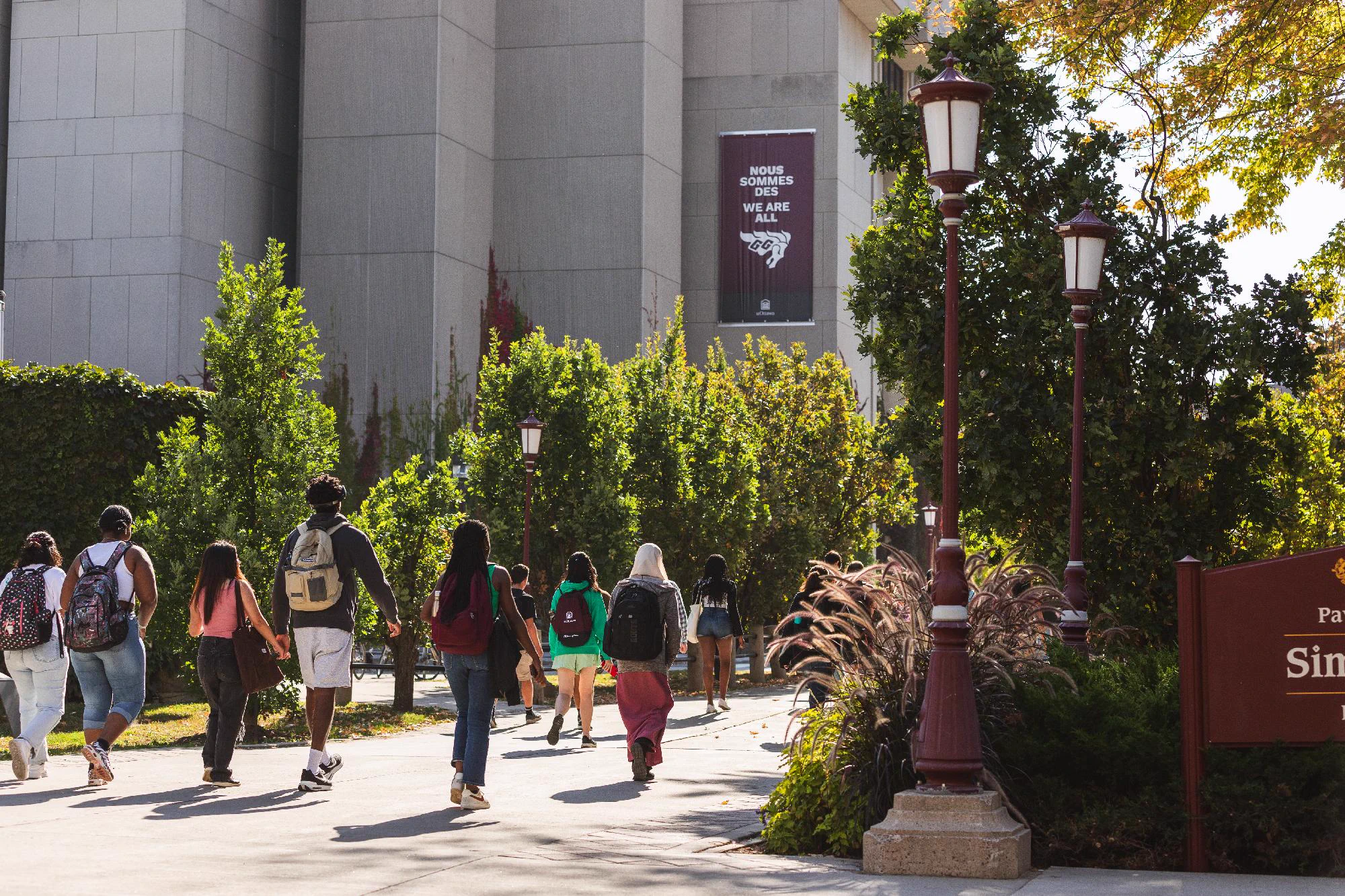 People are walking on the Grande Allée / Kichi Mìkàns at the University of Ottawa.