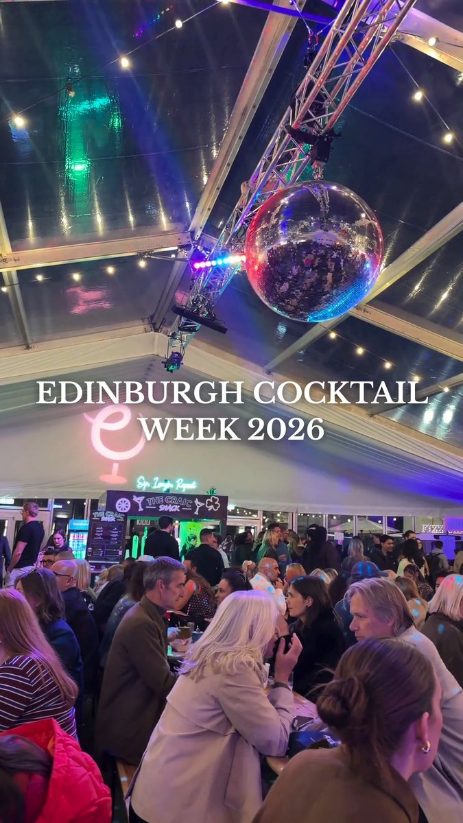 Crowded Edinburgh Cocktail Week 2026 event venue featuring a mirrored disco ball, string lights, and neon signage for "Sir Lanky Roam" and "The Craig Snag" as attendees socialize under a transparent tent roof. The image captures the lively atmosphere of the Cocktail Village pop-up mentioned in the post.