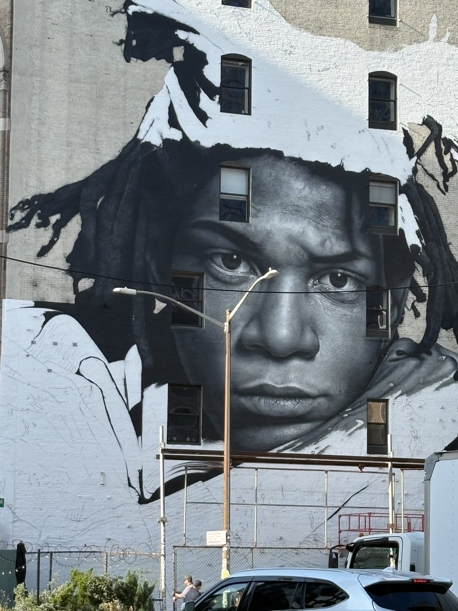 evgrieve's tweet photo. WIP look at the 6-story-tall mural of Jean-Michel Basquiat taking shape on the SW corner of the Bowery at Great Jones. The work is by New Zealand-based street artist Owen Dippie. Basquiat lived two buildings west at 57 Great Jones St. when he died in 1988. https://t.co/pj4AEbFxoB