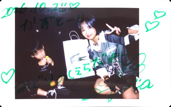 A Polaroid photo of a young woman and a child posing together with a shopping bag, covered in green and black handwritten text and hearts.