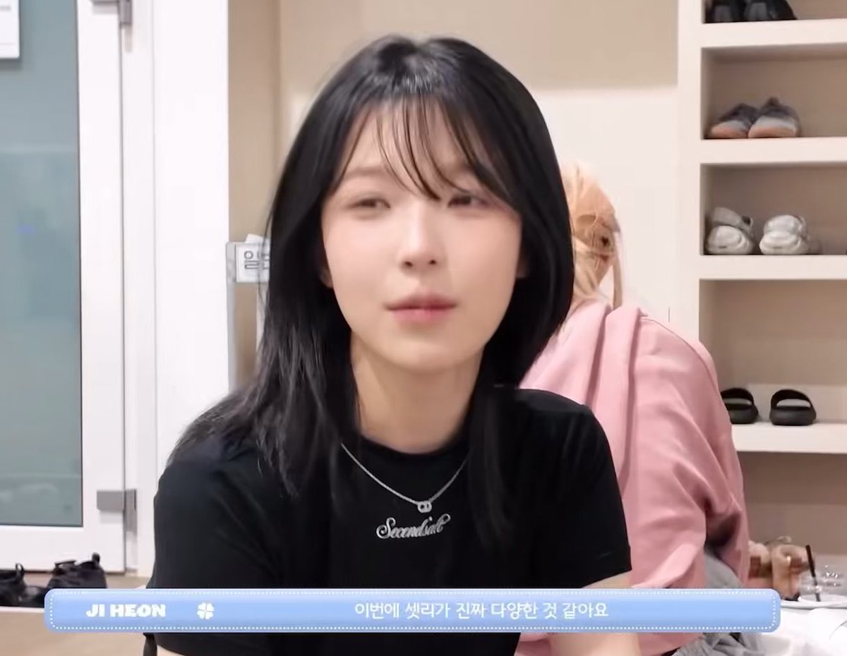 A woman with long dark hair and bangs, identified as "JI HEON" by the on-screen text, wears a black t-shirt with a "Secondtul" necklace while speaking, with the Korean caption reading "이번에 썼리가 진짜 다양한 것 같아요." The post's comment about her expressive speaking face matches her mid-conversation expression captured in the frame.