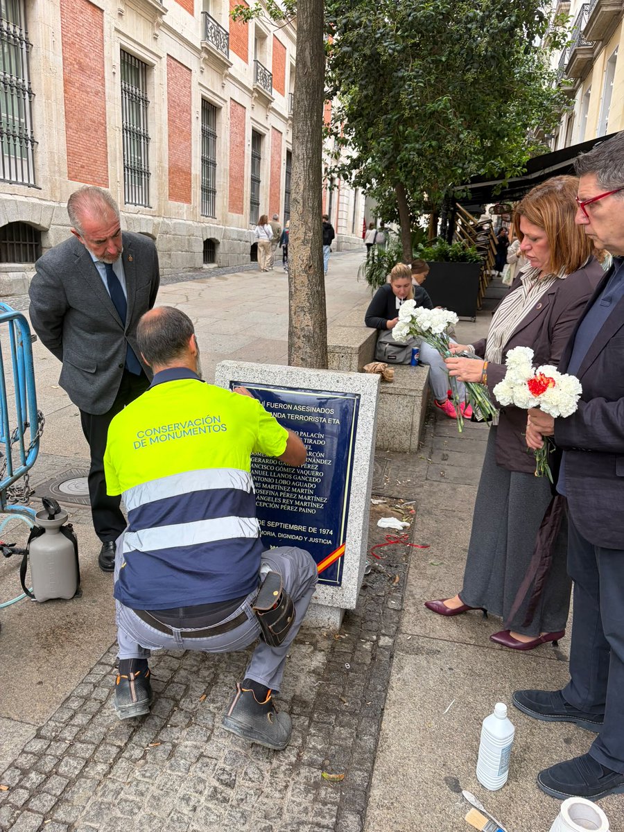 VidalQuadras's tweet photo. La presidenta de la AVT depositando flores en la placa recordatoria de las víctimas del atentado de ETA en la cafetería Rolando de la calle Correo mientras la limpian tras haber sido vandalizada por los acampados en Sol. https://t.co/2BK3QnQvLF